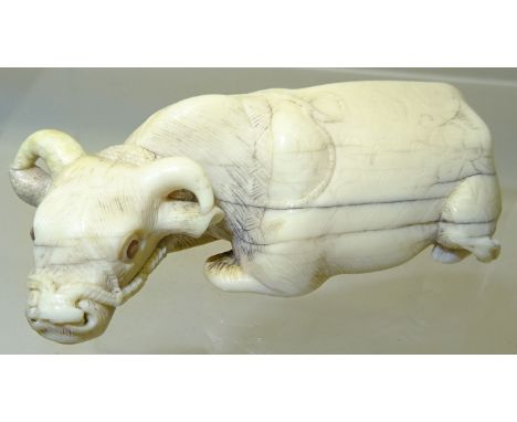 A Japanese Netsuke in the form of a carved ivory water buffalo, 2 1/2" (6.5cms) long. 