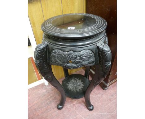 A CHINESE EBONIZED HARDWOOD STAND with circular top and carved lower detail and under tier shelf, 76 cms high