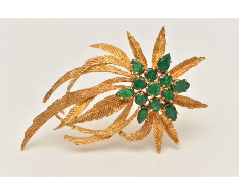 A YELLOW METAL EMERALD SET SPRAY BROOCH, textured spray of leaves, set with a cluster of circular cut and pear cut emeralds, 