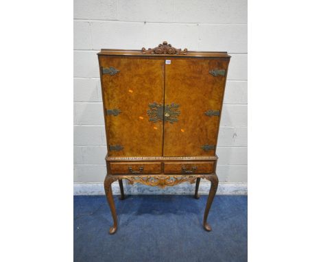 A QUEEN ANNE STYLE WALNUT DRINKS CABINET, with a foliate crest, the double doors enclosing a fitted interior, above two drawe