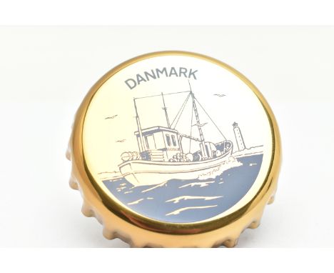 A GEORG JENSEN NOVELTY BOTTLE OPENER, designed as a bottle top with a blue ship and 'Danmark' detail to the top, stamped 1981
