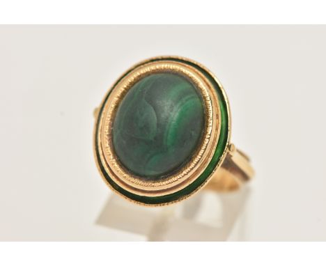 A YELLOW METAL MALACHITE AND GREEN ENAMEL DRESS RING, of an oval form set with an oval cut malachite cabochon, collet set wit