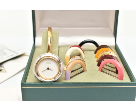 A CASED GUCCI BANGLE WATCH WITH ELEVEN COLOURED INTERCHANGABLE BEZELS, WITH BOOKLET AND INTERNATIOAL WARRANTY CARD, the watch