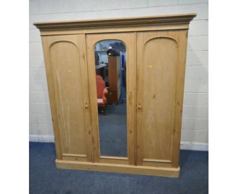 A 19TH CENTURY PINE TRIPLE DOOR WARDROBE, with an overhanging cornice, a central mirror door, the right hand door enclosing v