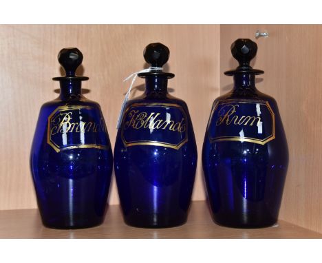 A SET OF THREE EARLY 19TH CENTURY BRISTOL BLUE GLASS BARREL SHAPED DECANTERS, with original faceted stoppers decorated with  