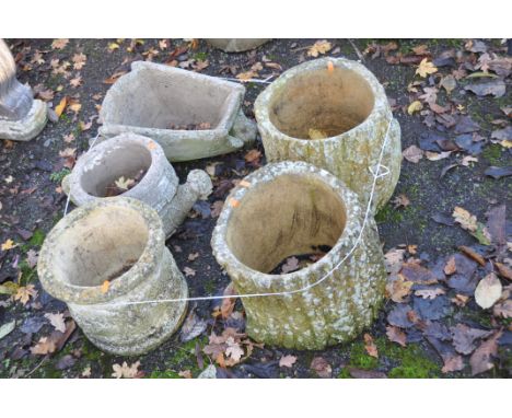 A COLLECTION OF WEATHERED COMPOSITE PLANTERS, two in the form of hollowed out tree stumps 29cm high, a wheel barrow, a wateri