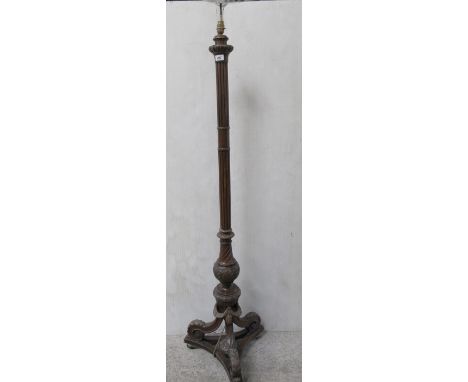 A late 19th century oak standard lamp in the Regency style, the carved baluster and fluted column above a tri-form scroll sup