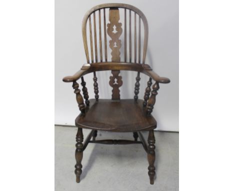 A 19th century Windsor stick-back elbow chair, high arched back with pierced fret carved splat and saddle seat, with ring-tur