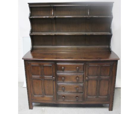 A modern reproduction dark oak dresser, the two-shelf plate rack on dresser base, central bank of four drawers flanked by two