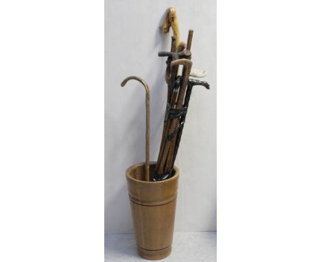 A wooden coopered stick stand with various walking canes to include a faux bamboo example, one with a horn-effect handle and 