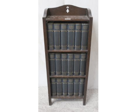 An early 20th century oak three-tier bookcase, 76 x 34cm,  with eighteen volumes of 'Charles Dickens library' illustrated by 