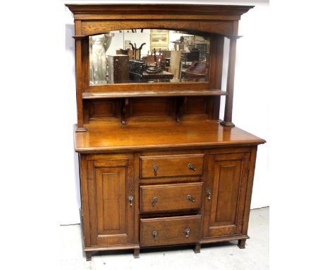 An early 20th century oak mirror-back sideboard, rectangular mirror above single shelf to rectangular raised panels over thre