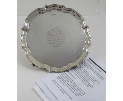 A George V hallmarked silver salver with curving rim to four scrolling supports, inscribed 'Presented by the Corporation of M