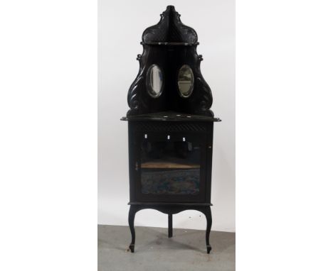 Victorian ebonised freestanding corner cabinet, upper section carved and shaped outline, inset with two oval mirrors, below a