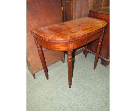 A 19th century mahogany folding card table lined with green baize, the frieze and top with ebony stringing on turned cylindri