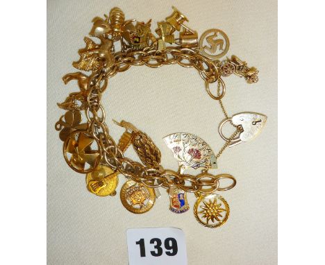 Heavy 9ct gold bracelet with padlock clasp and hung with 21 charms, some 14ct and some 9ct. Charms include bee, cuckoo clock,