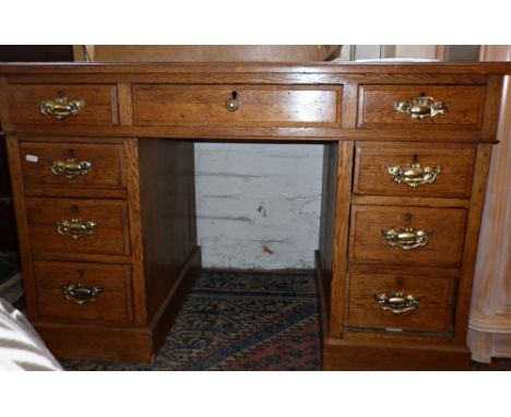 Light oak kneehole pedestal desk of nine drawers with tooled green leather top and having brass handles