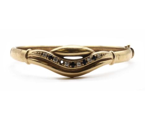 A gold cubic zirconia set bangle, the shaped upper half set with cubic zirconia to plain lower half, with box clasp and figur