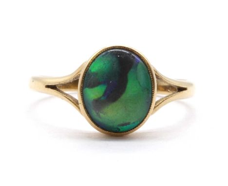 A gold single stone black opal ring,an oval cabochon opal, rub set, to split shoulders and a plain shank, tested as approxima