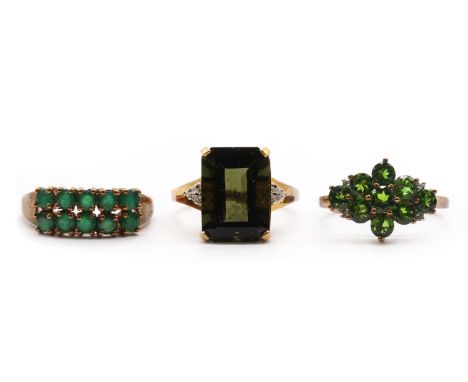 Three 9ct gold rings,comprising a moldavite and diamond ring, a two row emerald ring, and a chrome diopside and diamond clust