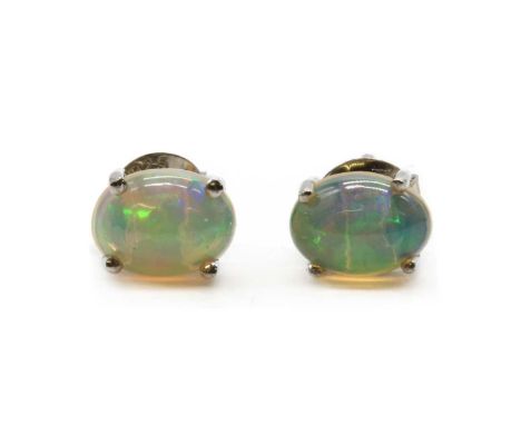 A pair of silver single stone opal stud earrings, with an oval cabochon opal, approximately 8 x 6mm, claw set to post and but