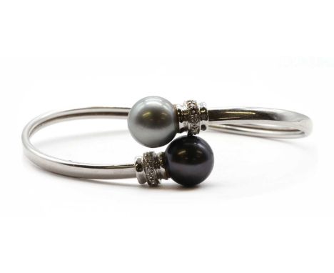 A white gold cultured Tahitian pearl and diamond torque bangle, of crossover design, with a grey and a black cultured Tahitia
