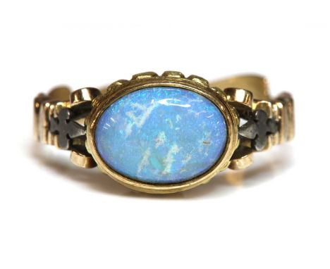 An antique style single stone opal ring, with an oval cabochon opal, rub set in a closed back gadroon collet, to scrolling sc