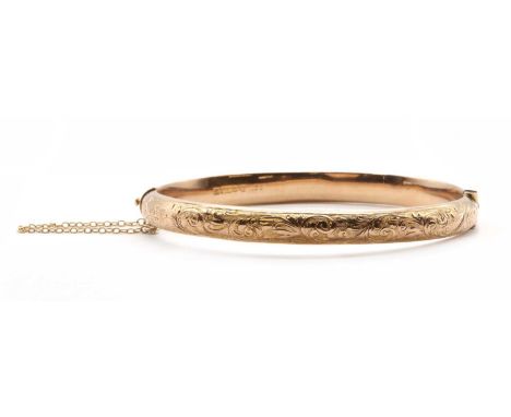 A 9ct gold hollow oval hinged bangle, with engraved decoration to the upper half and a plain lower half, with concealed twist