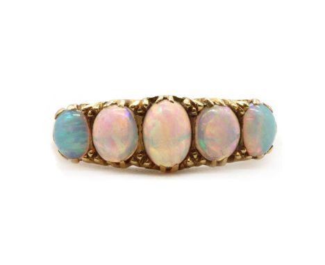 An 18ct gold five stone opal ring, a row of graduated oval cabochon opals, claw set to a carved scroll head, with tapered sho