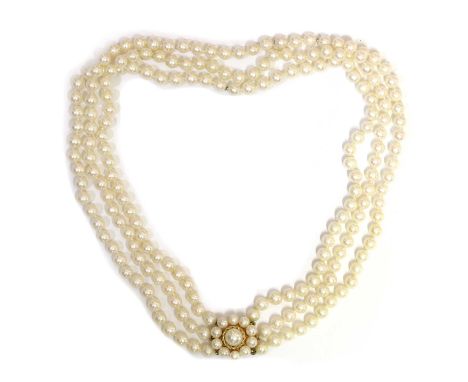 A three row uniform cultured pearl necklace,5 to 5.5mm in size, strung knotted to a 9ct gold cultured pearl set cluster clasp