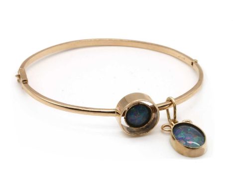 A gold opal triplet bangle, the upper half rub set with an opal triplet, to plain lower half and concealed box clasp, suspend
