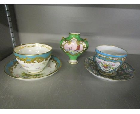 Two 19th century decorative cups and saucers, one decorated with sprigs of flowers and the other with birds in flight and a R