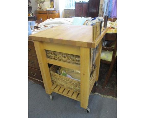 A modern light oak butchers style kitchen island on castors, having two baskets, a knife rail with a quantity of mixed kitche