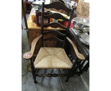 A 19th century oak ladder back carver chair with a rush seat, on turned legs 