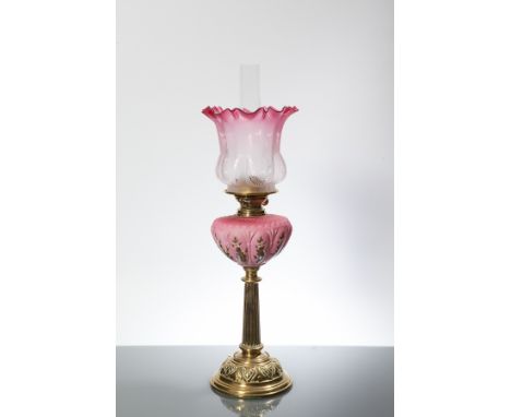 VICTORIAN BRASS OIL LAMP WITH CRANBERRY GLASS SHADE 
with pink floral font, on circular base, 67cm high; and with a spare fun