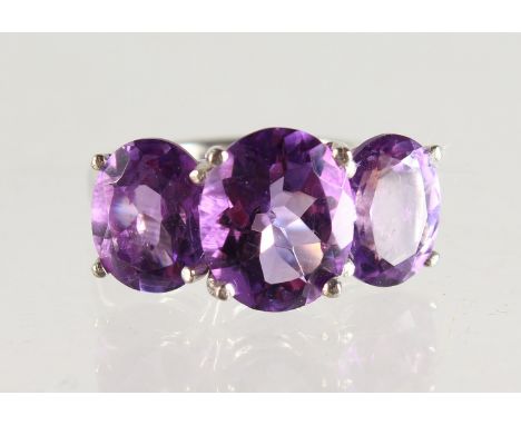 A SILVER THREE STONE AMETHYST RING.