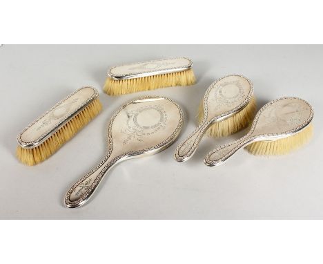 A FIVE PIECE ENGRAVED SILVER DRESSING TABLE SET, comprising hand mirror and four brushes. London 1918.