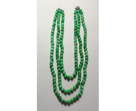 A GOOD JADE THREE-ROW NECKLACE, with diamond and ruby set clasp.