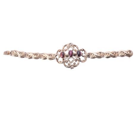 A mid Victorian gold and garnet bracelet, circa 1860, the central open work scroll panel set with three oval cabochon garnets