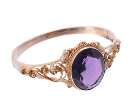 A late Victorian amethyst hinged bangle, circa 1900, the oval mixed cut amethyst collet set within a ropetwist border, to a s