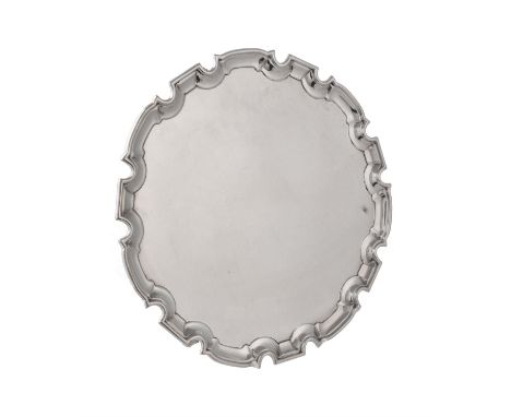 A silver shaped circular salver by William Hutton & Sons Ltd., Sheffield 1929, with a raised moulded border and on three foli