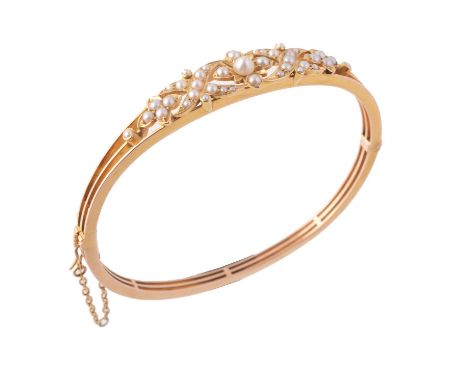 An Edwardian half pearl hinged bangle, circa 1910, the central flowerhead set with a bouton pearl with half pearl set petals 
