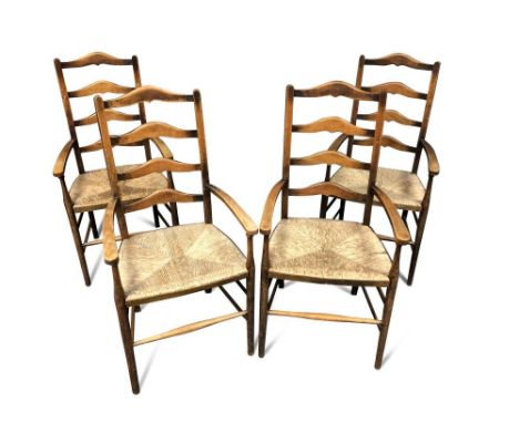 A set of four Arts &amp; Crafts ladder back armchairs, each with shaped back rails to rush seats and raised on tapering cylin