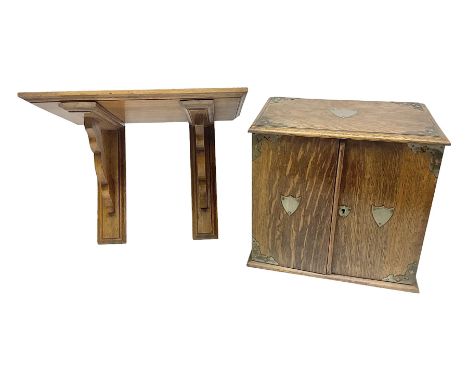 Early 20th century oak smokers cabinet, with brass shield shaped mounts, opening to reveal a compartmentalised interior with 