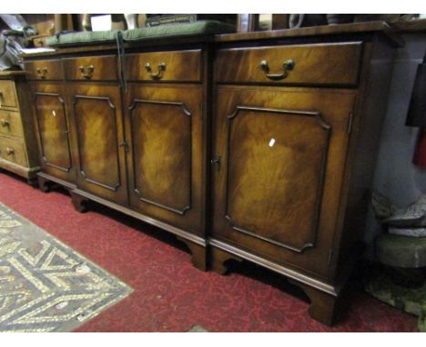A reproduction mahogany shallow breakfront sideboard fitted with four frieze drawers over four moulded panelled doors raised 