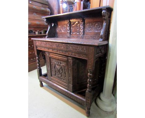 An antique oak side table/dresser with carved panels, trailing fruit and floral detail, etc, the shallow raised back with fur