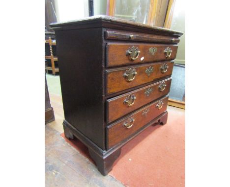 An unusually small (75cm) 18th century oak countrymade chest of four long graduated drawers with brush slide raised on bracke