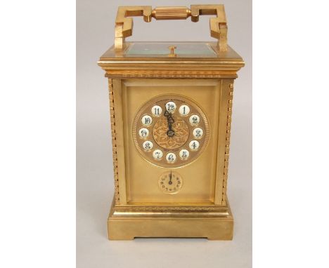 Gilt brass carriage clock with shaped cast case, the gilt mask fitted with inset enamel Arabic numerals and subsidiary dial, 