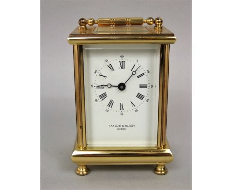 Taylor & Bligh of London gilt brass carriage clock, the square enamel mask with Roman and Arabic numerals, upon on four shape