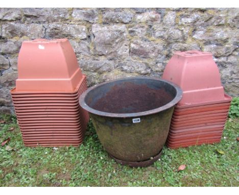 A cast iron planter of circular waisted form with flared rim, together with a quantity of moulded plastic pots (to simulate t